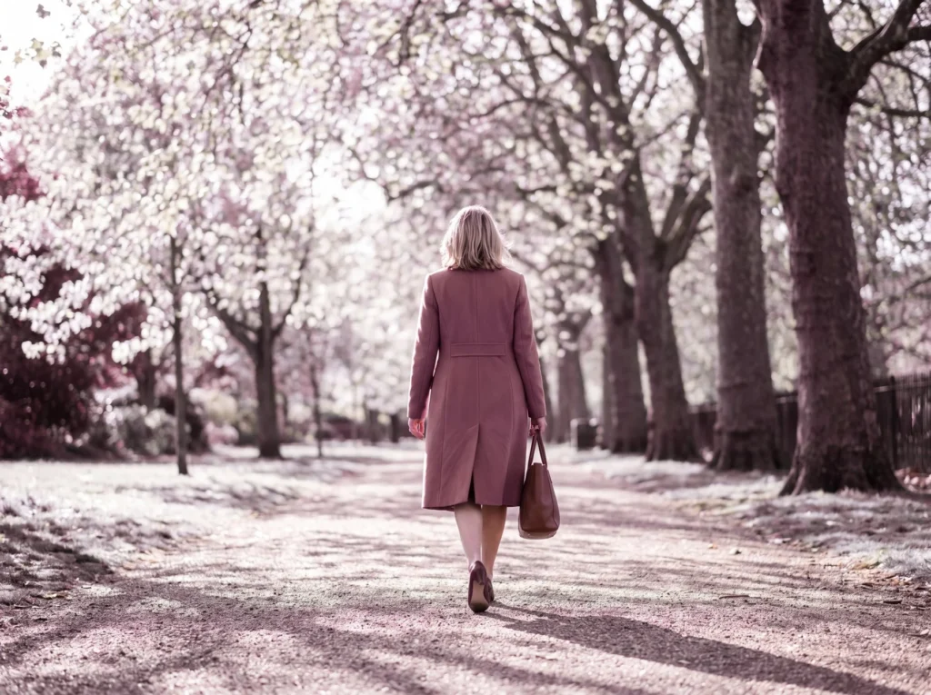 Woman walking along a tree-lined path covered in blossom