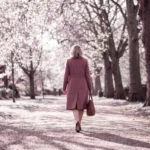 Woman walking along a tree-lined path covered in blossom