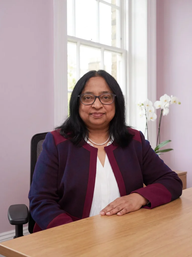 Miss Roopa Bangari sitting at her desk in a consulting room